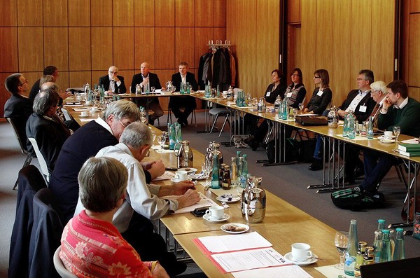 Auf dem Bild zu sehen ist die Diskussionsrunde der Tagung an in einem Viereck aufgestellten Tischen