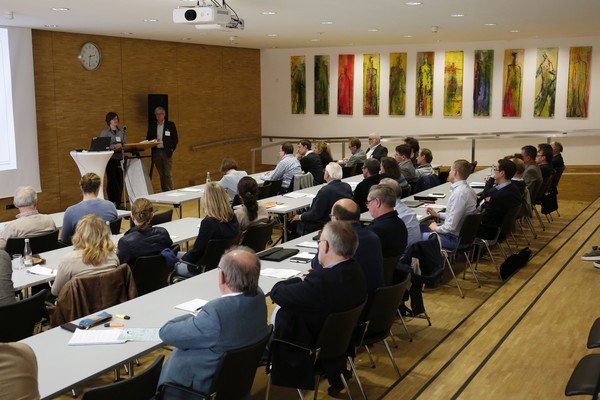 Wir sehen das Plenum von hinten, welches einem Vortrag zuhört