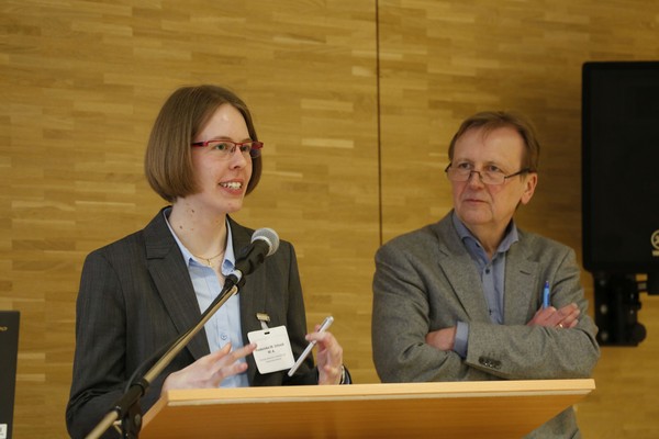 Auf dem Bild sehen wir, wie Frederieke Schnack ihr Thema präsentiert. Neben ihr steht Professor Doktor Werner Freitag