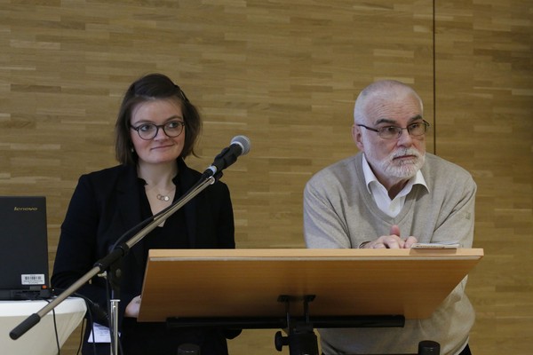 Auf dem Bild sehen wir, wie Friederike Scholten über ihr Thema spricht. Neben ihr steht Professor Doktor Wilfried Reininghaus